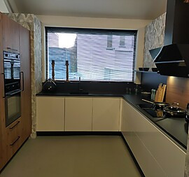 Greeploze witte hoogglans keuken met houtdecor accenten en koolstofzwart werkblad