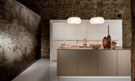 Deze luxe keuken, bestaande uit een hoge keukenwand en een keukeneiland, werkt kalm door de beige en crème-tint. Het ontwerp is symmetrisch en de meubels zijn onverstoord door grepen of versieringen. Zuordnung: Stil Luxe keukens, Planungsart Keuken met keukeneiland
