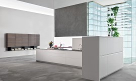 Strakke lijnen zonder onnodige versierselen, helder wit en een moderne uitstraling zijn de kenmerken van deze keuken in eilandvorm. Het rechte keukenblok bestaat uit onderkasten met deurtjes en grote lades die ideaal zijn voor het opbergen van serviesgoed, potten en pannen. De rechterhoek van de keuken wordt omsloten door half hoge kasten. Op de achtergrond is een zeer bijzonder glazen open kastsysteem te zien dat aan het plafond is opgehangen. Zuordnung: Stil Design-keukens, Planungsart Detail keukenontwerp