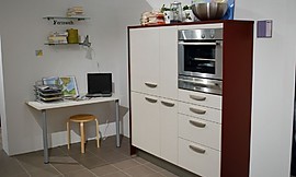 Voorbeeld van een werkplek in de hoek van de keuken. Een simpel tafelblad aan de muur met twee tafelpoten. Keukenkast met gebroken witte fronten en wangen van donker hout. Ingebouwde magnetron-oven-combinatie. Zuordnung: Stil Design-keukens, Planungsart Keuken met keukeneiland