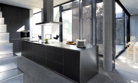 Het karakteristieke kookeiland b3 met flinterdun roestvrij stalen aanrechtblad gecombineerd met zwarte greeploze fronten. De kastenwand achteraan is in de wand ingebouwd. Zuordnung: Stil Design-keukens, Planungsart Keuken met keukeneiland