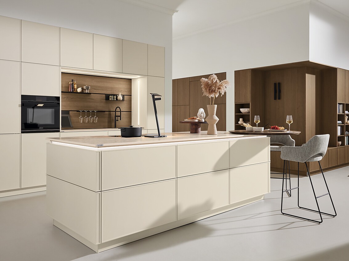 Deze keuken combineert een tijdloos-modern ontwerp met een greeploze afwerking en een mat, licht unidecor. Met een functionele planningstype met eiland en bar, biedt deze keuken een perfecte balans tussen esthetiek en gebruiksgemak. Zuordnung: Stil Moderne keukens, Planungsart Keuken met keukeneiland