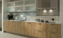 Moderne houten keuken met lichte eiken fronten gecombineerd met dunne witte aanrechtbladen en hangkasten. De deurtjes van de hangkasten zijn voorzien van matglas. Zuordnung: Stil Moderne keukens, Planungsart Open keuken (woonkeuken)
