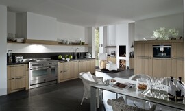 Landelijke keuken met modern accent. Hier ziet u wat een groot fornuis, typisch voor landelijke keukens, voor de keuken betekent. Hier is de afzuigkap onopvallend verwerkt in een schouw. De kasten hebben relatief brede wangen en een stenen aanrechtblad. Zuordnung: Stil Landelijke keukens, Planungsart L-vormige keuken