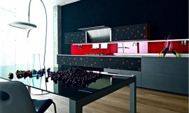 Design keuken van gerecycled glas. Greeploze grijze en zwarte fronten met rode stippen, felrode keukenachterwand. De afzuigkap zit in de bovenkast ingebouwd en kan open- en dichtgeklapt worden. Deze keuken laat zien wat fronten met creatieve opdruk voor het totaalbeeld kunnen betekenen. Zuordnung: Stil Design-keukens, Planungsart Keuken met keukeneiland