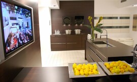 Hier ziet u een voorbeeld ervan, hoe een televisie elegant in een keuken kan worden ingebouwd. Het apparaat zit achter een wand die dezelfde tint heeft als de keukenmeubels. Zuordnung: Stil Design-keukens, Planungsart Binneninrichting van de keuken