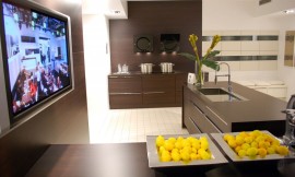 Hier ziet u een voorbeeld ervan, hoe een televisie elegant in een keuken kan worden ingebouwd. Het apparaat zit achter een wand die dezelfde tint heeft als de keukenmeubels. Zuordnung: Stil Design-keukens, Planungsart Keuken met zitgelegenheid