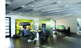 Deze keuken valt op door zijn futuristische design: een combinatie van metallic tinten en neon geel. De keuken bestaat uit twee elementen. Ten eerste het gedeelte met fornuis en spoelbak. Rechts en links daarvan gaan twee strakke zuilen naar boven die boven de spoelbak en het fornuis met elkaar worden verbonden, als het ware een hoekige boog. De neon verlichting weerspiegelt in de mat metallic fronten. Roestvrijstalen aanrechtblad. Het tweede element van de keuken is een blok met hoge kasten, waarin in het midden de oven is opgenomen. Zuordnung: Stil Design-keukens, Planungsart keukenblok