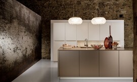 Deze luxe keuken, bestaande uit een hoge keukenwand en een keukeneiland, werkt kalm door de beige en crème-tint. Het ontwerp is symmetrisch en de meubels zijn onverstoord door grepen of versieringen. Zuordnung: Stil Luxe keukens, Planungsart Keuken met keukeneiland