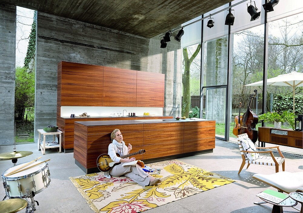 Deze keuken met vlakke houtesthetiek valt op door gebrek aan grepen en zijn slanke aanrechtbladen. Optisch wordt het beeld gedomineerd door de prachtige horizontale tekening van het hout. De keuken roept een loungy sfeer op. Zuordnung: Stil Moderne keukens, Planungsart keukenblok