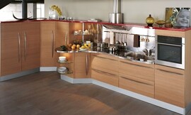 Keuken met houten fronten en lange grepen. Aanrechtblad in speelse, golvende vorm. Stalen achterwand bij het werkgedeelte. Een rode lijst (boven) verbindt de verschillende gedeeltes van de keuken optisch. Zuordnung: Stil Landelijke keukens, Planungsart Open keuken (woonkeuken)