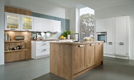 Hout contrasteert bijna altijd mooi met gebroken wit. In deze keuken komt de houttint terug in het aanrechtblad en in de achterwand links. De fronten zijn kader fronten met grepen. Hier is tevens gebruik gemaakt van verlichting door spots aan de onderkant van de keukenkastjes. Zuordnung: Stil Klassieke keukens, Planungsart Detail keukenontwerp