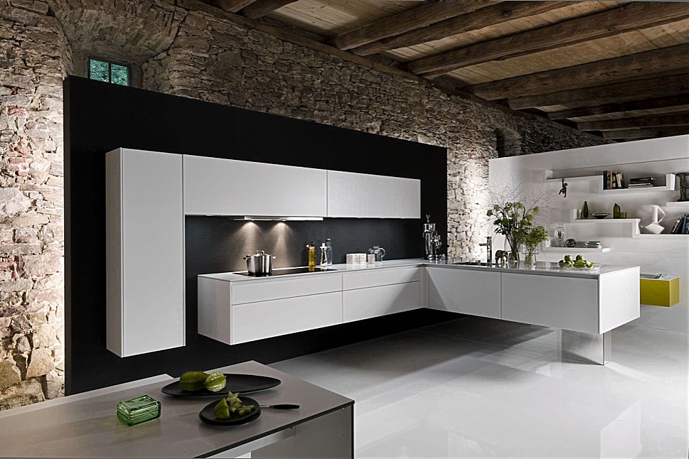 In deze moderne zwevende designkeuken komt de L-vorm twee keer terug. Eén keer als hoge kast tegen de muur met twee brede bovenkasten daarnaast. Ook het ondergedeelte vormt een L. Op het ene gedeelte van de L kan er worden gekookt, de afzuigkap is in de kast daarboven vrijwel onzichtbaar opgenomen. Het andere deel van de L is o.a. voorzien van de spoelbak. De greeploze strakke kasten en het dunne aanrechtblad zorgen voor een rustige uitstraling. Zuordnung: Stil Luxe keukens, Planungsart L-vormige keuken