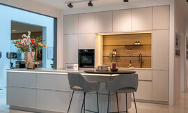 Ervaar de verfijning van de greeploze, lichte designkeuken met een modern keukeneiland en ronde eetbar. Deze keuken straalt stijl en elegantie uit, dankzij zijn minimalistische frontdeuren en praktische indeling. Zuordnung: Stil Moderne keukens, Planungsart Keuken met zitgelegenheid