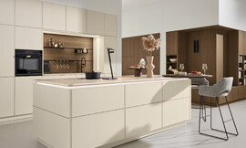 Deze keuken combineert een tijdloos-modern ontwerp met een greeploze afwerking en een mat, licht unidecor. Met een functionele planningstype met eiland en bar, biedt deze keuken een perfecte balans tussen esthetiek en gebruiksgemak. Zuordnung: Stil Moderne keukens, Planungsart Keuken met zitgelegenheid