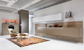 Deze zwevende keuken heeft naast aan de wand hangende witte bovenkasten ook beige hangende onderkasten. De oven is op praktische werkhoogte opgenomen in de half hoge beige kasten. Greeploos en met strakke vormgegving valt deze ruimte nauwelijks meer te herkennen als keuken en zorgt voor een symbiotische overgang van keuken naar woonkamer. Zuordnung: Stil Design-keukens, Planungsart Open keuken (woonkeuken)