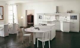 Klassieke, open keuken met zithoek aan kookeiland. Symmetrisch keukenblok met schouw (afzuigkap). Tint: wit in contrast met een prachtige donkere vloer. Links staat ook nog een grotere eetkamertafel. Zuordnung: Stil Klassieke keukens, Planungsart L-vormige keuken