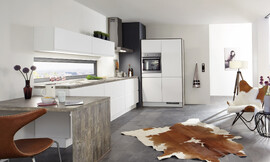 Deze witte keuken overtuigd met een rechtlijnig en modern ontwerp. Praktisch is de naastliggende aanzettafel, die een zitmogelijkheid biedt. Zuordnung: Stil Moderne keukens, Planungsart Open keuken (woonkeuken)