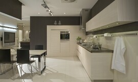Deze keuken leunt optisch sterk op de lichte tint van pijnhout, hier verwerkt in de greeploze fronten en de wandkast. Een subtiel aanrechtblad in een donkerdere bruin/grijstint contrasteert met het hout. Moderne keuken. Zuordnung: Stil Moderne keukens, Planungsart Keuken met keukeneiland
