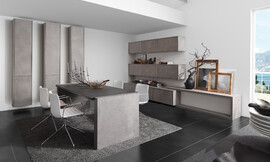 Uitbreiding van de keuken naar het woonbereik met massief houten en betonnen oppervlakten. De overgang tussen keuken en eetkamer wordt steeds geleidelijker. Het waardevolle binnenwerk van puur hout concurreert met gemak met andere gevestigde meubelfabrikant in het woonsegment. Zuordnung: Stil Design-keukens, Planungsart Open keuken (woonkeuken)