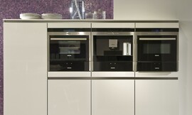 Hier ziet u een detail van de hangende hoogkast met drie apparaten en fronten met greeplijsten. Ook het paarse mozaïek is goed zichtbaar. Zuordnung: Stil Moderne keukens, Planungsart keukenblok