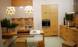 Houten keuken in U-vorm met zitgelegenheid. Fronten in licht houten tint en mat witte tint met grepen. Een onderkast loopt onder de tafel door. Zuordnung: Stil Klassieke keukens, Planungsart Keuken met keukeneiland