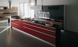 Design kookeiland met rode hoogglans fronten met greeplijsten en een dun, zwart glanzend aanrechtblad. Een design-afzuigkap hangt boven het fornuis, en is verbonden met het meubel d.m.v. een glazen plaat. Aan de achterkant van het meubel is een houten bartafel ingericht met zitgelegenheid op barkrukken. Zuordnung: Stil Design-keukens, Planungsart Keuken met zitgelegenheid