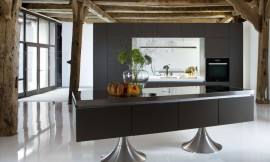Vrij in de ruimte maar toch in zichzelf gesloten: met deze keuken wordt zichtbaar hoe design en functionaliteit in harmonie kunnen treden. Twee ronde metallic poten dragen dit matzwarte meubel. Een keukenwand met interessant verlichtingsconcept maakt het geheel af. Zuordnung: Stil Design-keukens, Planungsart U-vormige keuken
