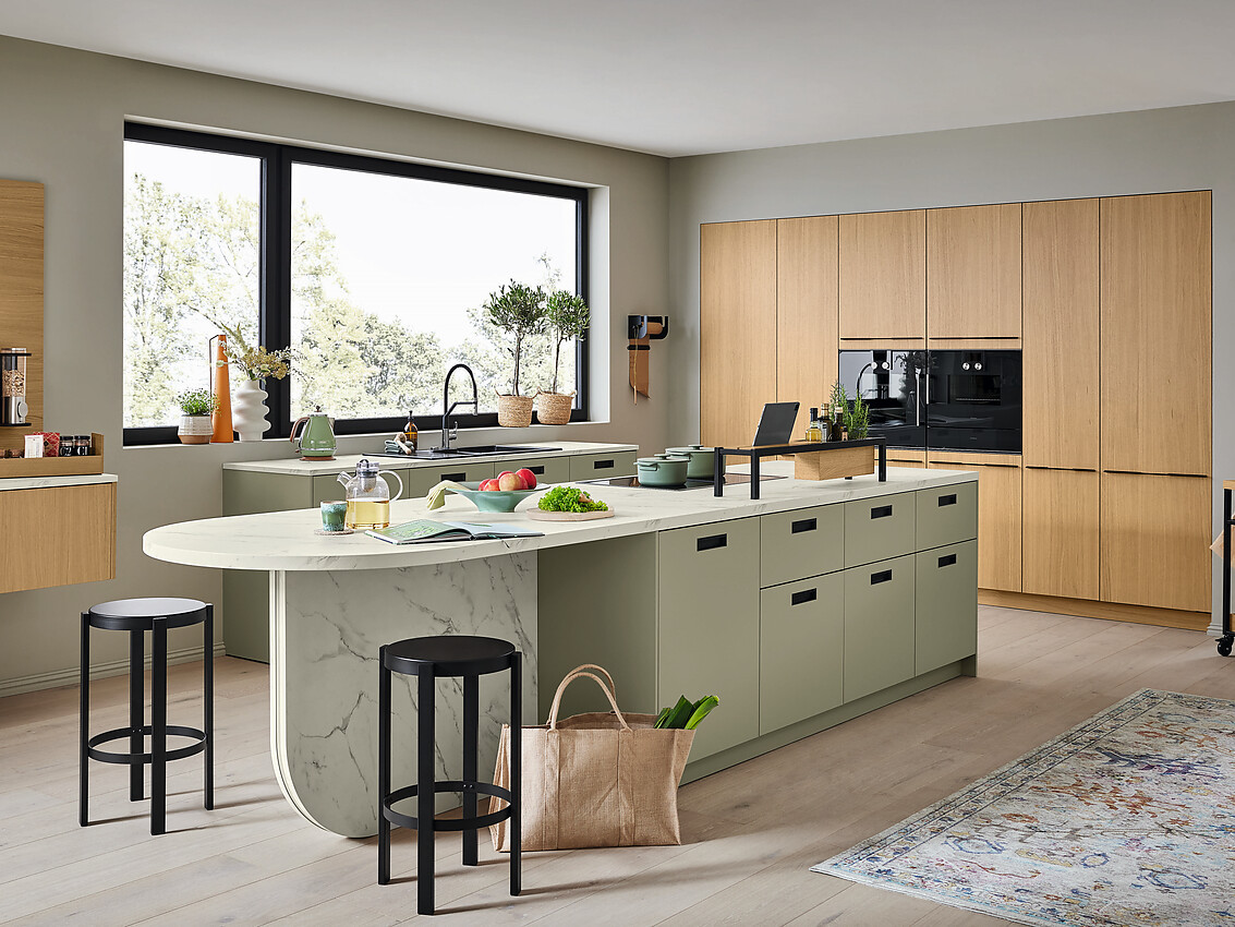 Deze keuken combineert een echt eikenfineer en eenkleurig frontdecor voor een helder, modern design. De strategische lay-out met eiland, bar en zitgelegenheid maakt het ideaal voor zowel koken als gezellig samenzijn. Zuordnung: Stil Design-keukens, Planungsart Keuken met keukeneiland