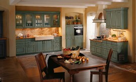 Rustieke landelijke keuken met ingemetselde afzuigkap. Opvallend hoge gootsteen en bovenkasten met glazen deurtjes. Vele ornamenten sieren deze landelijke keuken. Ook de vloer is voorzien van een bijzonder patroon. Zuordnung: Stil Landelijke keukens, Planungsart L-vormige keuken