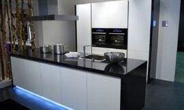 Design keuken met hoogglans zwarte wangen en aanrechtblad. Greeploze fronten en opvallende blauwe verlichting uit de sokkel van het keukeneiland. Zuordnung: Stil Design-keukens, Planungsart Keuken met keukeneiland