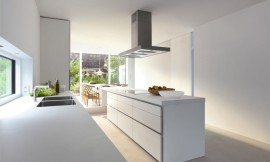 Deze witte designkeuken heeft een kookeiland en een wandblok. Op het kookeiland is een fornuis opgenomen en daarboven is de afzuigkap geplaatst. Daarnaast wordt er veel plaats geboden voor het voorbereiden van de maaltijd. De grote lades onder het fornuis zijn optimaal voor het opbergen van pannen en andere kookaccessoires. In het wandblok bevindt zich de dubbele spoelbak met handige mengkraan. Ook hiernaast wordt er op het werkblad veel plaats geboden voor het voorbereiden van uitgebreide maaltijden. Het dikke aanrechtblad heeft dezelfde witte tint als de fronten, waardoor het geheel erg homogeen werkt. De rustige sfeer die de keuken uitstraalt wordt ook niet verstoord door grepen of andere tierelantijnen. De gootsteen is naadloos in het aanrechtblad verwerkt en daardoor zeer makkelijk schoon te houden. Zuordnung: Stil Design-keukens, Planungsart Keuken met keukeneiland