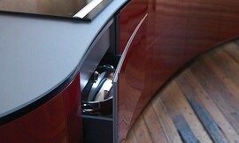 Vrijstaand, licht afgerond keukenblok met design afzuigkap. Mat grijs werkblad en hoogglans bordeauxrode fronten. Greeploze fronten. Zuordnung: Stil Design-keukens, Planungsart Open keuken (woonkeuken)