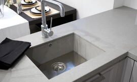 Hier ziet u een gootsteen die van hetzelfde materiaal gemaakt is als het aanrechtblad, en niet boven de rand van het werkblad uitkomt. De gootsteenstop is tegelijk een filter voor grove voedselresten. Zo wordt verstopping voorkomen. Zuordnung: Stil Moderne keukens, Planungsart Open keuken (woonkeuken)