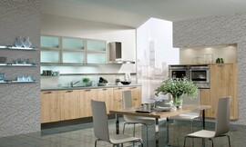Het lichte hout van de fronten contrasteert met de lichtblauwe glazen bovenkast, de reflecterende vloer en de speelse accenten in het behang. Klassieke keuken met aparte eetkamer- of keukentafel. Zuordnung: Stil Klassieke keukens, Planungsart keukenblok