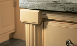 Detailfoto: Pilaster met groeven (zandgeel gelakt) onder aanrechtblad van natuursteen. Zuordnung: Stil Landelijke keukens, Planungsart Keuken met keukeneiland
