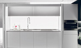 De glazen achterwand met led-verlichting maakt deze keuken tot eyecatcher. Zuordnung: Stil Luxe keukens, Planungsart Keuken met keukeneiland