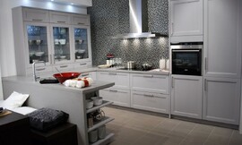 U-vormige keuken met blauwgrijze cassette fronten en een opvallende achterwand met mozaïek. Op het aanrechtblad links staan opzetkasten met glazen deurtjes. Zuordnung: Stil Design-keukens, Planungsart Keuken met keukeneiland