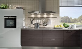 Detailfoto van het aanrecht. Eiken decorfronten, een grijs stenen werkblad en kleine tegels tegen de muur. Zuordnung: Stil Moderne keukens, Planungsart L-vormige keuken