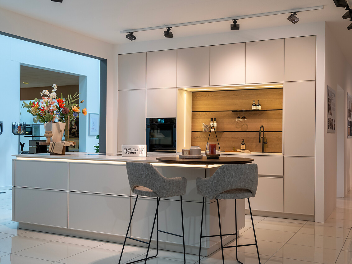 Ervaar de verfijning van de greeploze, lichte designkeuken met een modern keukeneiland en ronde eetbar. Deze keuken straalt stijl en elegantie uit, dankzij zijn minimalistische frontdeuren en praktische indeling. Zuordnung: Stil Moderne keukens, Planungsart Keuken met keukeneiland