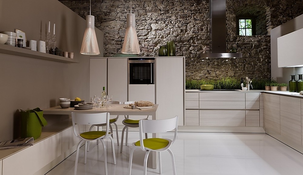 Deze lichtvoetige keuken in de L-vorm speelt met een subtiel contrast tussen lichte houttinten en gebroken witte vlakken. Fronten met greeplijsten houden de keuken optisch kalm. Hier ziet u de ingebouwde zitgelegenheid. Zuordnung: Stil Klassieke keukens, Planungsart Keuken met zitgelegenheid