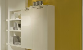 Hier ziet u een hangende hoogkast tegen de achtergrond van een mango gele wand. Links is een boekenkast in de wand ingebouwd. Zuordnung: Stil Moderne keukens, Planungsart keukenblok