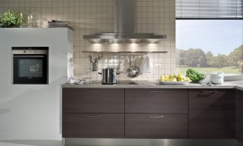 Detailfoto van het aanrecht. Eiken decorfronten, een grijs stenen werkblad en kleine tegels tegen de muur. Zuordnung: Stil Moderne keukens, Planungsart L-vormige keuken