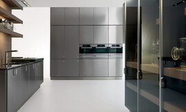 Deze moderne keuken voldoet aan alle wensen. Rechts een hoogkast met donker glas, achter een hoogkast met solide metallic fronten met subtiele grepen en ingebouwde apparatuur en links een werkblad en fornuis Zuordnung: Stil Design-keukens, Planungsart keukenblok