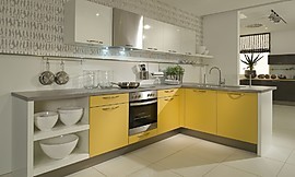 L-vormige keuken met mango gele en witte fronten en een grijs granieten aanrechtblad. De afzuigkap past onopvallend tussen de andere bovenkasten en de spoelbak op het uitstekende keukenblok is voorzien van een glasplaat om spetters tegen te houden. Zuordnung: Stil Moderne keukens, Planungsart Keuken met zitgelegenheid