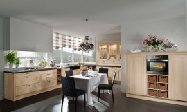 Hier ziet u een landelijke keuken in een L-opstelling met een extra blok met half hoge kasten. De kaderfronten met lichte houttint en de vakken met manden versterken het landlijke effect van deze keuken. De vier grote en twee normale lades onder het fornuis bieden genoeg plaats voor het kookgerei. In hetzelfde deel van de keuken bevindt zich ook de spoelbak. In het andere deel van de L-opstelling zijn er opzetkasten geplaatst, die de landelijke keuken ook een klassieke touch geven. De oven en koelapparatuur zijn opgenomen in de halfhoge kasten. Zuordnung: Stil Landelijke keukens, Planungsart Keuken met keukeneiland