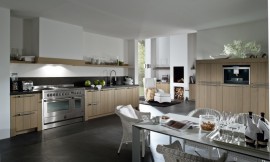Landelijke keuken met modern accent. Hier ziet u wat een groot fornuis, typisch voor landelijke keukens, voor de keuken betekent. Hier is de afzuigkap onopvallend verwerkt in een schouw. De kasten hebben relatief brede wangen en een stenen aanrechtblad. Zuordnung: Stil Landelijke keukens, Planungsart Keuken met keukeneiland