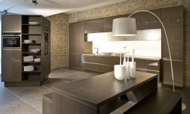 Deze moderne ééndelige keuken wordt afgemaakt door een vrijstaande kast waar zich twee apparaten in bevinden. De greeploze hoogglans fronten hebben net als het hout van de kast een bronzen tint. Zitgelegenheid aan aparte tafel. Zuordnung: Stil Moderne keukens, Planungsart Keuken met keukeneiland