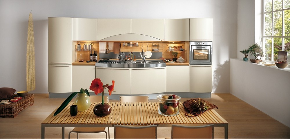 Moderne, deels greeploze keuken bestaande uit een brede, symmetrische keukenwand. Beige fronten contrasteren met metaaltinten en licht hout. Speels, golvend ontwerp. Een bijzondere tafel met smalle plankjes maakt het geheel af. Zuordnung: Stil Moderne keukens, Planungsart keukenblok