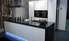 Design keuken met hoogglans zwarte wangen en aanrechtblad. Greeploze fronten en opvallende blauwe verlichting uit de sokkel van het keukeneiland. Zuordnung: Stil Klassieke keukens, Planungsart Detail keukenontwerp